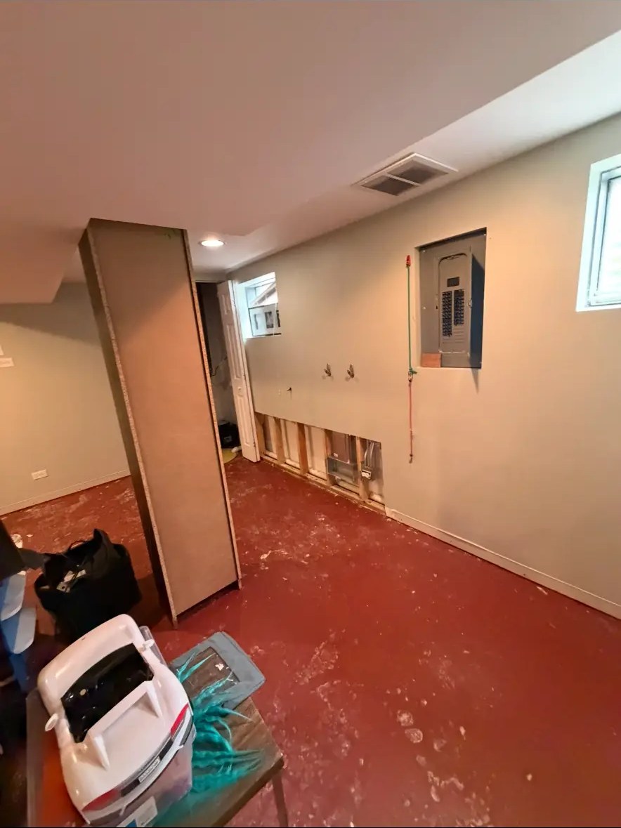 Basement before restoration with damaged lower walls and red flooring