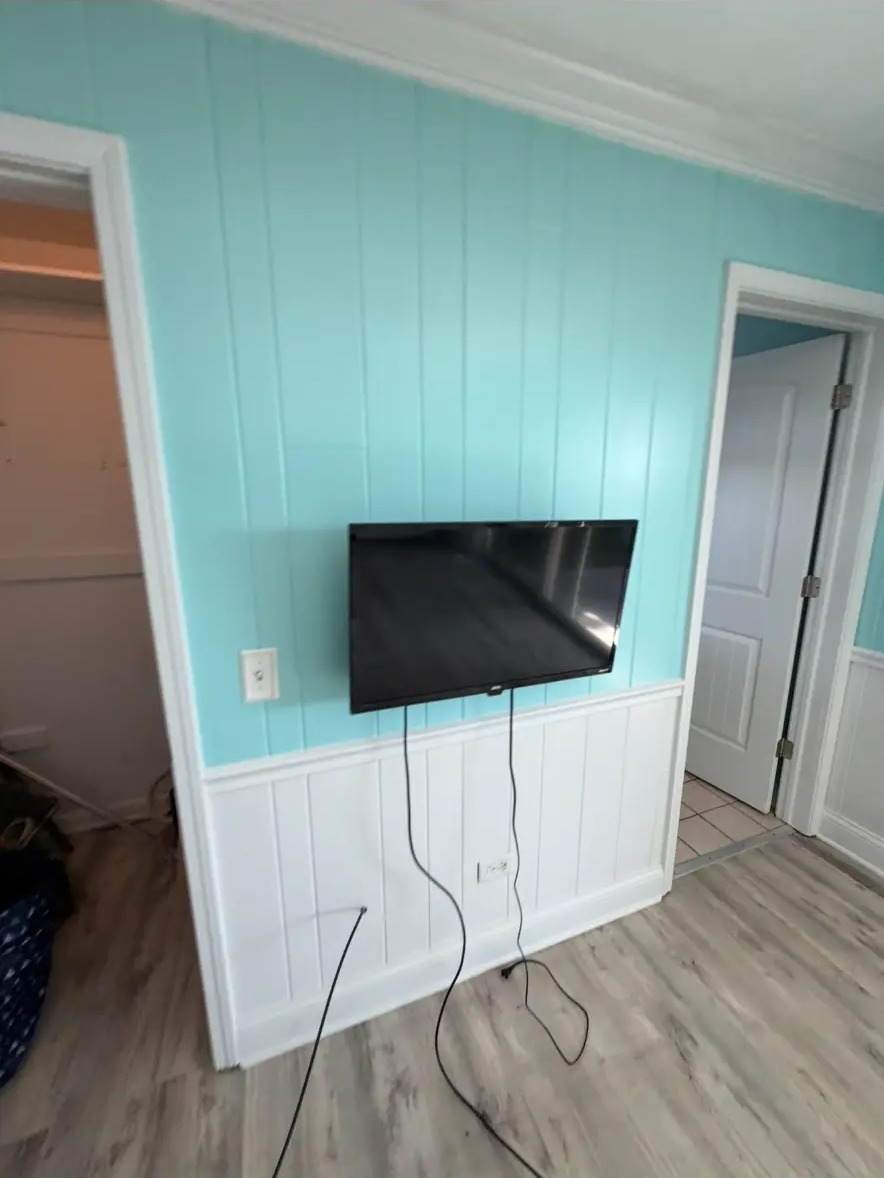 Bedroom wall with mounted TV and visible cables before repair